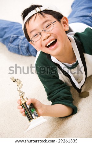 An asian boy excited about his winning sport medal and trophy