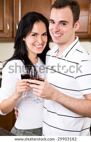 A beautiful interracial couple toasting wine in the kitchen