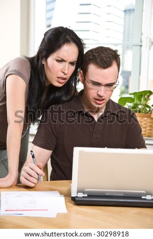 A stressed couple paying bills by using online banking at home