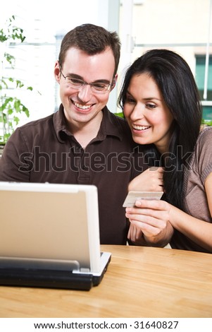 A happy couple holding a credit card shopping online