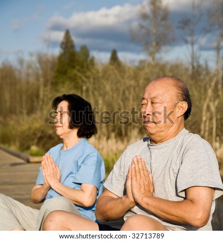 An active senior asian couple exercises and practices yoga and meditation