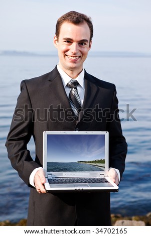 A portrait of a caucasian businessman holding a laptop outdoor (the image on the laptop was taken by me)