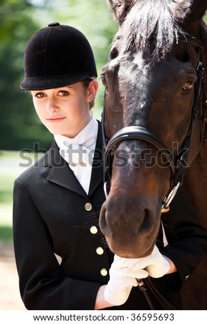 A caucasian girl getting ready for a horseback riding posing with her horse