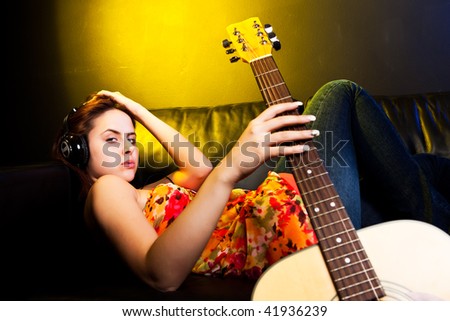 A shot of a beautiful caucasian woman lying down on the sofa listening music with headphones