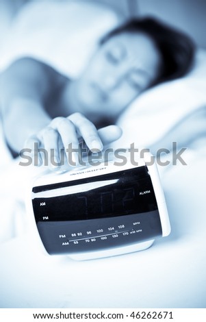 A sleeping black woman waking up to the sound of the alarm clock
