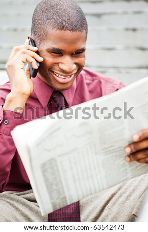 A portrait of a smiling black businessman reading newspaper outdoor