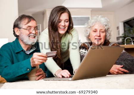 A portrait of a happy senior couple shopping online with the help from their granddaughter