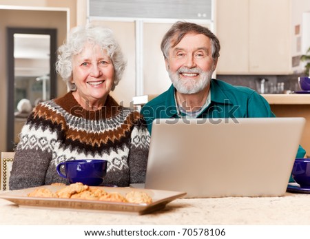 A portrait of a happy senior couple using computer at home