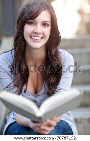 A shot of a smiling college student reading a book