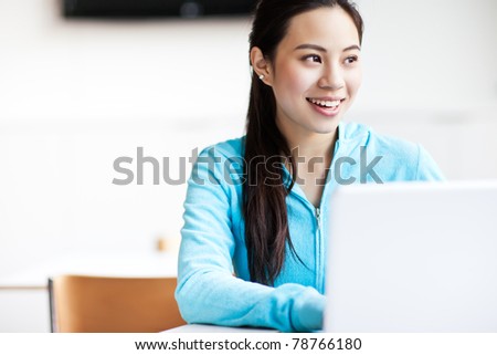 A shot of an Asian college student working on her laptop on campus