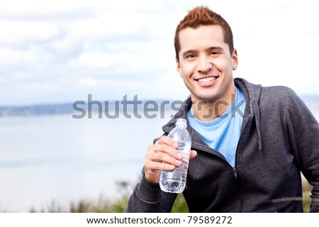 A shot of a mixed race man holding water bottle outdoor
