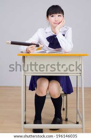 Asian girl student in school uniform studying with an oversize pencil