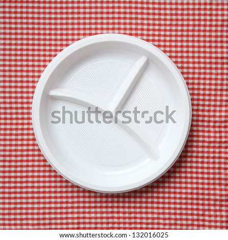 Empty plastic plate on a checkered cloth.