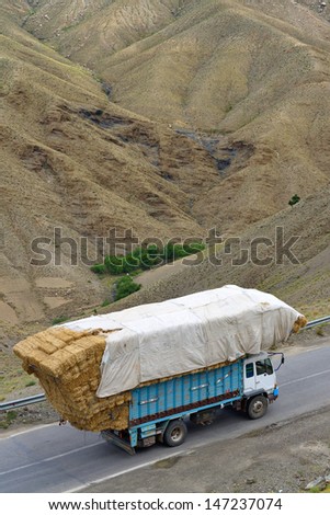ATLAS, MOROCCO - JULY 13: Overloaded truck staying on road, July 13, 2013 in Atlas Mountains, Morocco. Road in Atlas Mountains very popular tourist route in central Morocco.