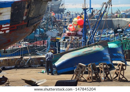 ESSAOUIRA - JULY 15: Unknown man repairing boat in harbor of Essaouira, Morocco, July 15, 2013. Essaouira is one of the most popular tourist place on Atlantic coast in Morocco.