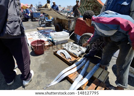 ESSAOUIRA - JULY 15: Unknown man sell fresh fish in harbor of Essaouira, Morocco, July 15, 2013. Essaouira is one of the most popular tourist place on Atlantic coast in Morocco.