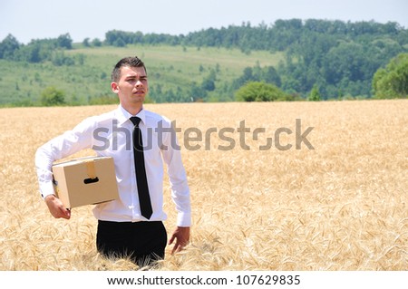 Business man delivering box in wheat