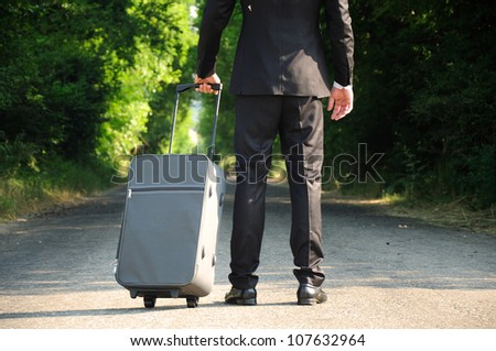Business man with luggage on road