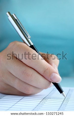 woman\'s hand writing entries in a notebook