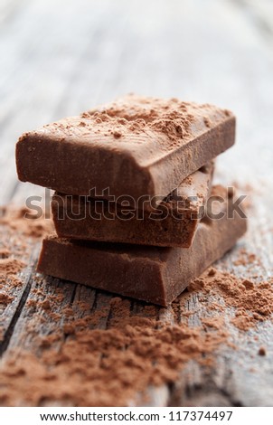 broken chocolate bar on a board sprinkled with cocoa