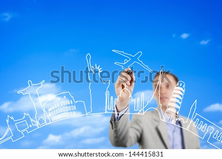 Business man drawing transport icon of a plane with major world cities as a backdrop on a glass wall.