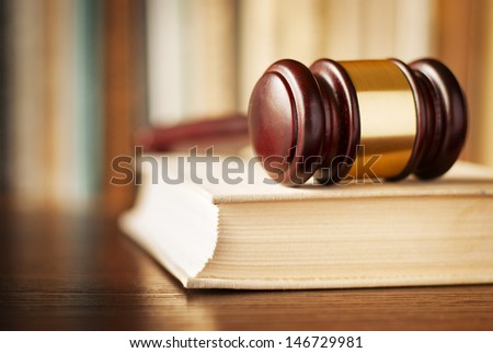 Conceptual image of law enforcement, justice and sentencing with a closeup view of a wooden judges gavel lying on a law book