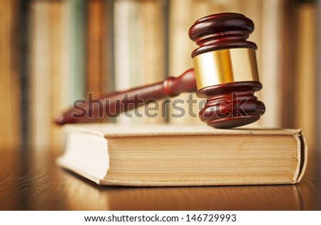 The verdict - a wood and brass judges gavel resting upright on top of a thick law book in a court