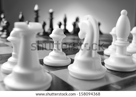 Game of chess with chess pieces lined up on their squares on either side of the board ready for a challenge with selective focus to one white pawn