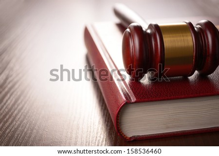Wooden judges gavel lying on a law book in a courtroom for dispensing justice and sentencing crimes