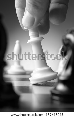 Conceptual image depicting making a strategic move with a hand moving a chess piece on a chessboard during a game of skill
