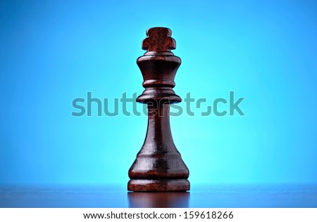 The winner, with a single retro wooden chess piece representing the king centred on a reflective surface on a blue background with a highlight and copyspace, conceptual image
