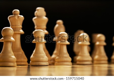 Low angle view of wooden chess pieces lined up on a chess board ready to commence a game of skill, planning and strategy