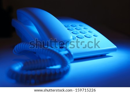 Close up view of the handset and keypad of a dial up telephone instrument with focus to the keys on the keypad in blue light
