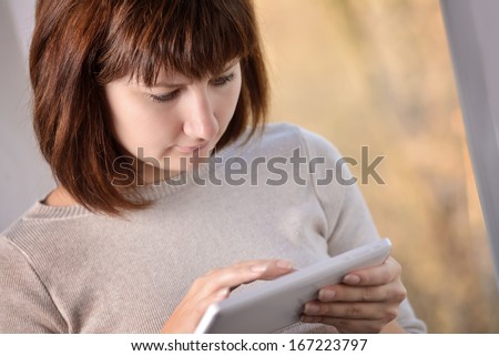 Attractive woman using a tablet-pc surfing the internet using finger touch on the touchscreen to access and navigate information