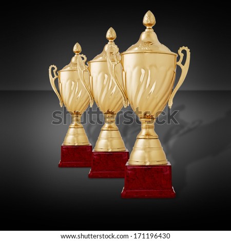 Receding row of three gold trophies to be awarded as prizes to the winner with lids and plinths standing on a dark grey background