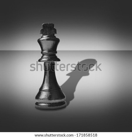 Black and white image of a king chess piece casting a shadow belonging to a pawn into a central highlight surrounded by vignetting