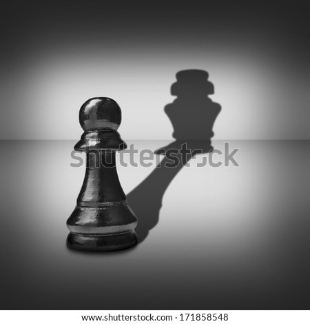 Conceptual image of dual identity with a pawn chess piece casting a shadow belonging to a king across a central highlight surrounded by a vignette in a black and white image