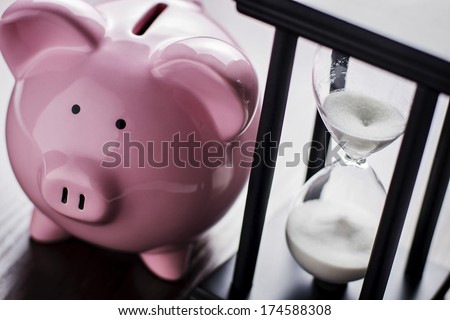 Pink ceramic piggy bank with an hour glass, conceptual of time running out to save for your retirement, a nest egg or to meet your dreams