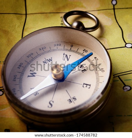 Closeup view of a portable magnetic compass lying on a map, conceptual of travel, tourism and exploration
