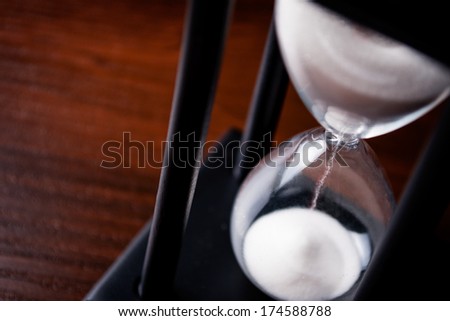High angle close up view of sand running through an hour glass or egg timer measuring the passing time and counting down to a deadline