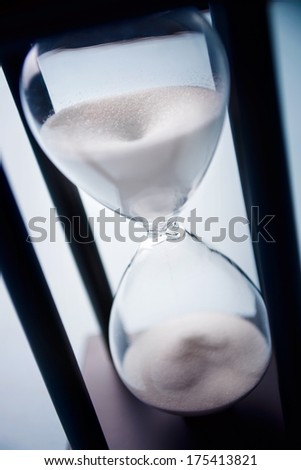 High angle close up view of sand running through an hour glass or egg timer measuring the passing time and counting down to a deadline