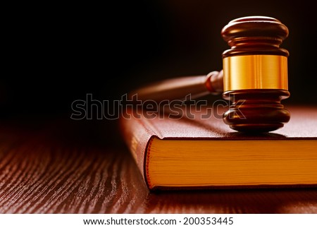 Wood and brass judges gavel standing upright on a law book conceptual of law enforcement and judgements in court