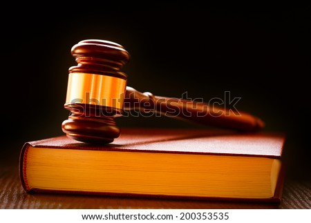 Wood and brass judges gavel standing upright on a law book conceptual of law enforcement and judgements in court