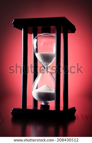 Egg timer or hourglass on a graduated red background in a conceptual image of passing time and time management