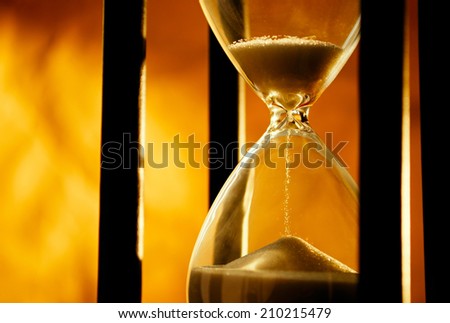 Conceptual image of measuring passing time with a close up view of sand running through an hourglass or egg timer on a golden background with copyspace