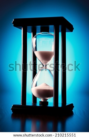 Egg timer or hourglass with blue sand running through the glass bulbs in a concept of passing time and time management