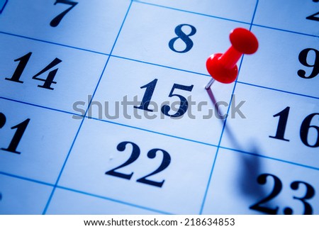 Red pin marking the 15th on a calendar as a reminder of an important event, close up low angle view