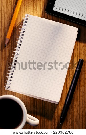 Notebook and Phone on Desk with Cup of Coffee as seen from Above with Various Writing Instruments