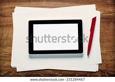 Overhead view of the blank white screen of a tablet and pen on blank paper ready for a meeting or taking notes in a communication concept, with copyspace