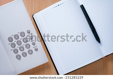 Close up Clean Notebook, Pen and Telephone on Wooden Desk of Telephone Operator.